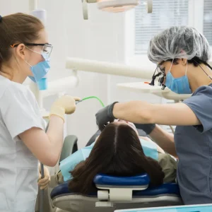 Orthodontic assistant helping dentist with dental procedure.