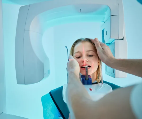 Orthodontic assistant helping a patient during a dental X-ray procedure.